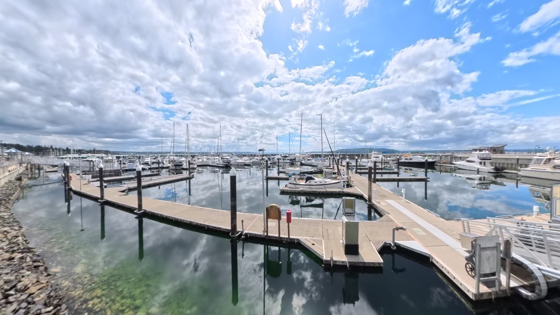 Aerial of Des Moines Marina at golden hour with the Olympic Mountains visible across Puget Sound